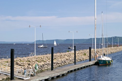 A peaceful waterfront scene with boats, a dock, and a clear blue sky over calm waters.