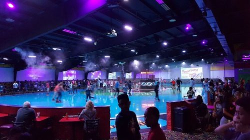 A vibrant roller skating rink filled with people, colorful lights, and a lively atmosphere.
