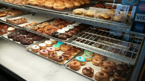 A display case filled with various donuts, including glazed, chocolate, and decorated options.