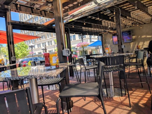 Outdoor dining area with empty tables, umbrellas, and condiments on a sunny day.