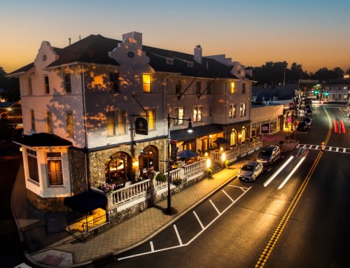 A charming hotel at dusk, with warm lights and a bustling street, showcasing a peaceful small-town atmosphere.