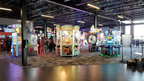 A vibrant arcade filled with colorful games and attractions, with people enjoying the entertainment.