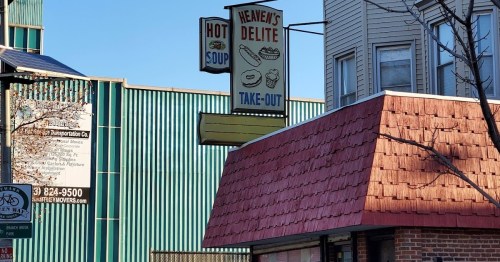 Sign for "Heaven's Delite" featuring "Hot Soup" and "Take-Out" with a red roof building in the foreground.