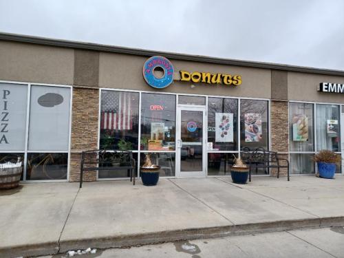Exterior of a donut shop with a sign reading "Donuts," featuring an American flag and an "Open" sign.