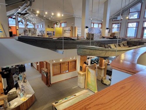 A view of a spacious indoor exhibit featuring a hanging boat and various displays in a well-lit environment.