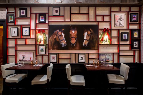 A stylish restaurant interior featuring a horse painting and framed artwork on a decorative wall.