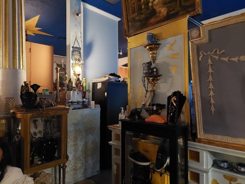 A cozy interior with ornate decor, featuring vintage furniture, artwork, and warm lighting.