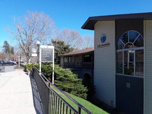 A sunny day view of the Lake Junaluska building with a sign and landscaped walkway.