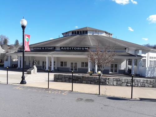 Exterior view of the George R. Stuart Auditorium, featuring a round roof and columns, with clear blue skies above.
