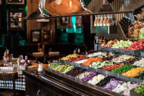 A vibrant salad bar filled with a variety of fresh vegetables, fruits, and toppings in a cozy restaurant setting.