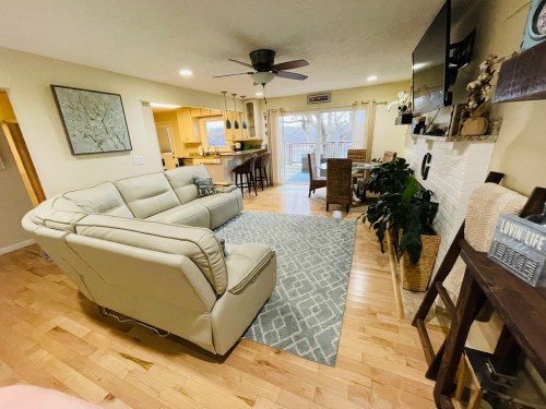 Cozy living room with light-colored furniture, a patterned rug, and a view of a patio through sliding glass doors.