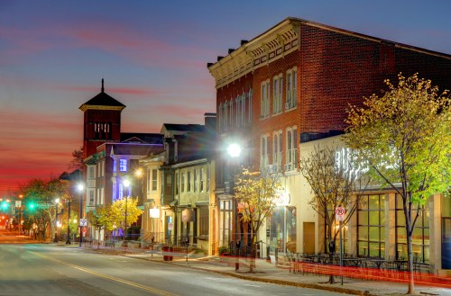 A charming street scene at dusk, featuring historic buildings, trees, and colorful sky with soft lighting.