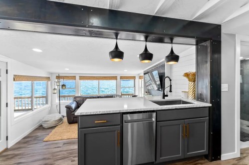 Modern kitchen with a black and white color scheme, featuring a sink, stainless steel appliances, and a view of the water.