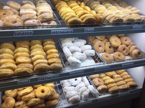 A display case filled with various types of donuts, including glazed, sugared, powdered, and cinnamon varieties.