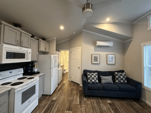 A cozy kitchen and living area with modern appliances, a blue couch, and light-colored walls.