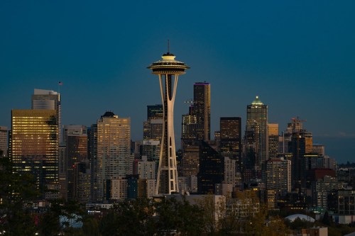 Seattle skyline at dusk featuring the Space Needle and illuminated skyscrapers against a twilight sky.
