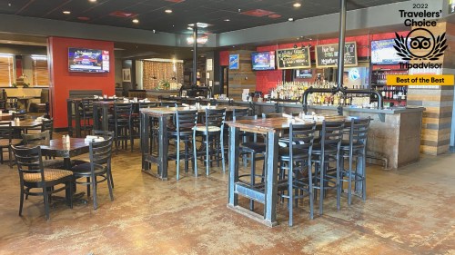 Interior of a restaurant featuring wooden tables, chairs, a bar, and multiple TVs displaying sports.