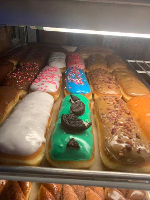 A display of colorful donuts with various toppings, including sprinkles, icing, and cookie pieces.