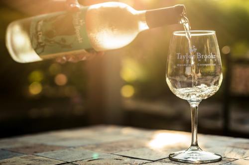 A bottle of wine is being poured into a glass, with sunlight creating a warm glow in the background.