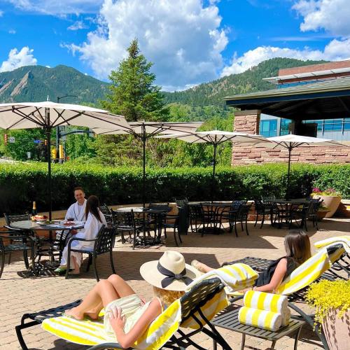 A sunny outdoor patio with people relaxing on lounge chairs, surrounded by mountains and umbrellas.