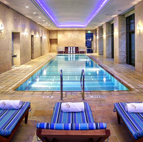 Indoor spa area featuring a swimming pool, lounge chairs, and soft lighting.