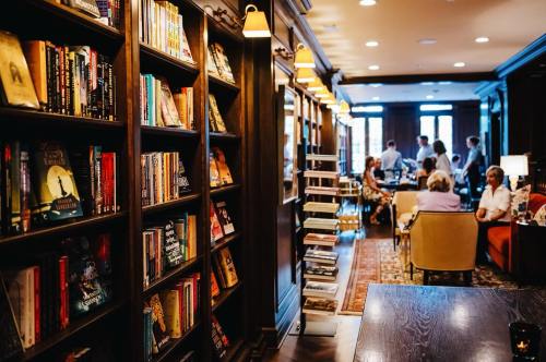 A cozy library with bookshelves, warm lighting, and people chatting in the background.