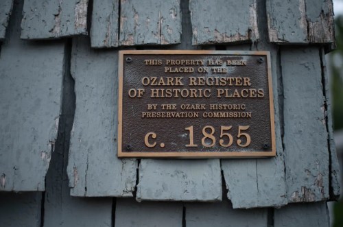 Plaque on a weathered building indicating it is on the Ozark Register of Historic Places, established c. 1855.