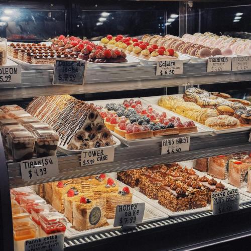 A display case filled with various desserts, including cakes, pastries, and macarons, all beautifully arranged.
