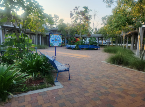 A peaceful outdoor pathway with benches, greenery, and a colorful mural in a serene garden setting.