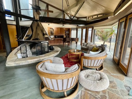 Cozy living room with circular seating, a central fireplace, and a piano in a modern, open-concept design.