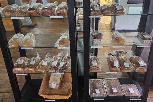 A display case filled with various baked goods, including loaves of bread and pastries, all packaged and labeled.