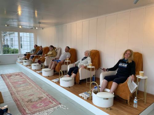 A group of people relaxing in spa chairs, enjoying a pampering session in a bright, modern space.