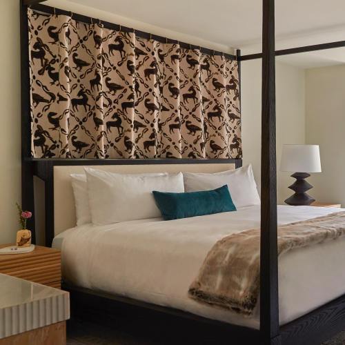 A stylish bedroom featuring a four-poster bed, patterned curtain, and modern lamp, with a cozy throw on the bed.