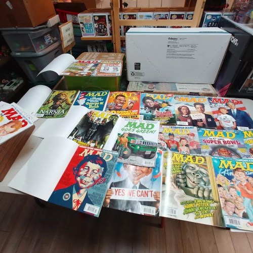 A table covered with various issues of MAD magazine and a few other books, including "Narnia" and a Super Bowl edition.