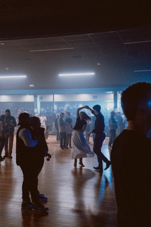 A lively dance floor with people enjoying themselves under dim lights and a smoky atmosphere.