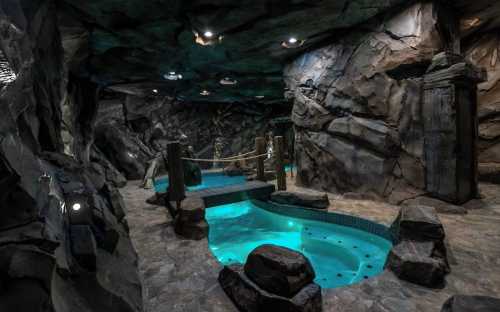 A luxurious cave-like spa with rock walls, a small pool, and ambient lighting creating a serene atmosphere.