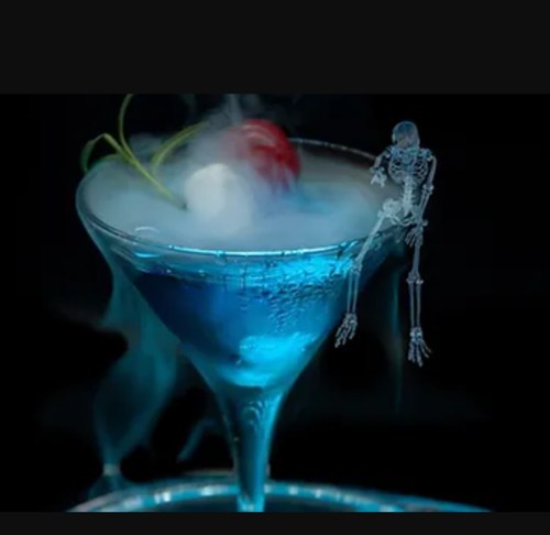 A blue cocktail with a cherry on top, featuring a small skeleton figure sitting on the rim and wisps of smoke.