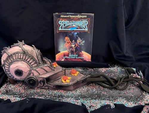 A detailed cake shaped like a Spelljammer ship, with colorful decorations and the Dungeons & Dragons game box in the background.