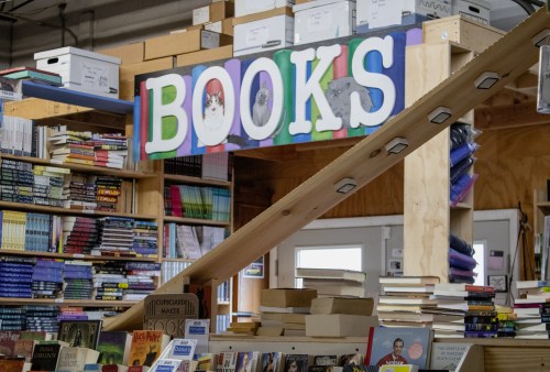 A colorful "BOOKS" sign above shelves filled with various books in a cozy bookstore setting.