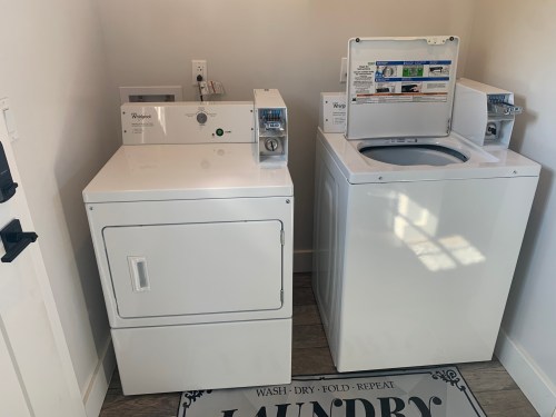 A white washer and dryer set in a laundry room, with a decorative laundry mat on the floor.