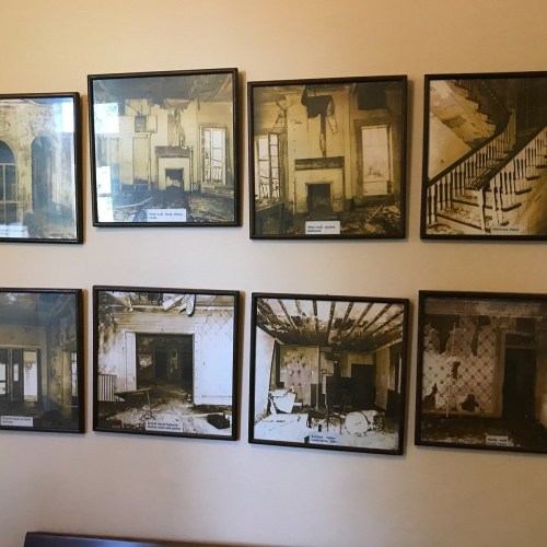 A wall displaying framed black-and-white photos of dilapidated rooms and staircases in an abandoned building.
