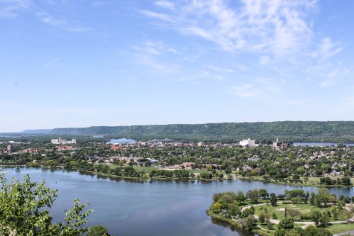 A scenic view of a river and city surrounded by greenery under a clear blue sky.