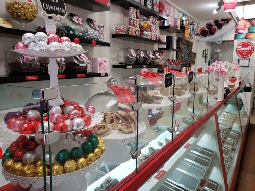 A colorful display of assorted candies and chocolates in a shop, featuring decorative trays and glass containers.