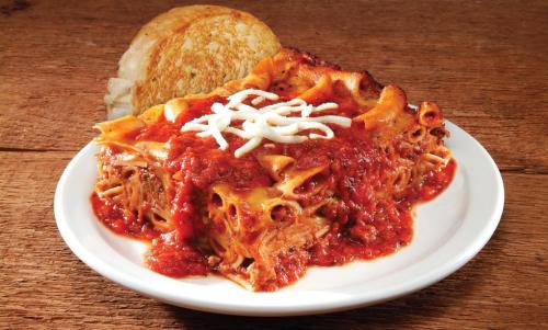A plate of lasagna topped with marinara sauce and mozzarella, served with a slice of toasted bread.