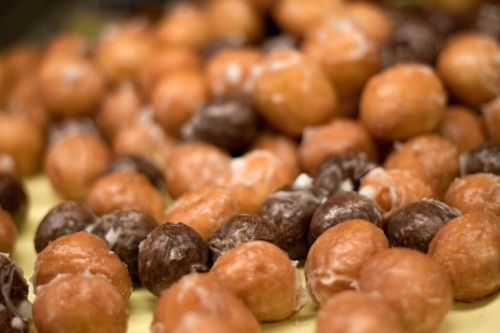A close-up of assorted glazed doughnut holes, featuring both light and dark chocolate varieties.