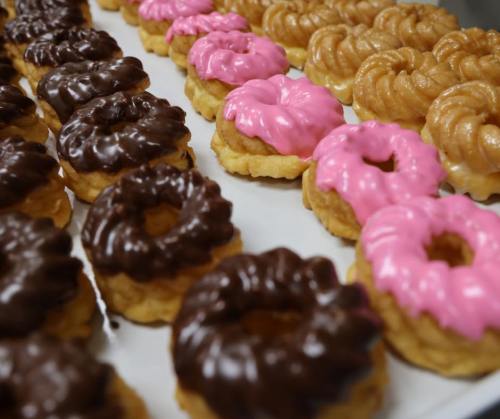 A close-up of a platter featuring chocolate and pink frosted donuts arranged in rows.