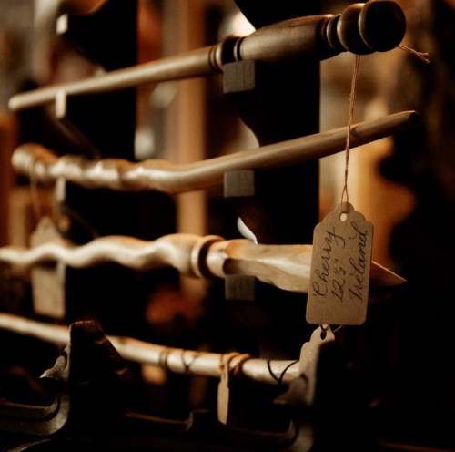 A close-up of wooden wands displayed on a rack, with a tag reading "Cherry, 12 inches."