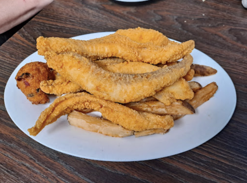 A plate of fried fish fillets, golden-brown, served with fries and a small fried ball.