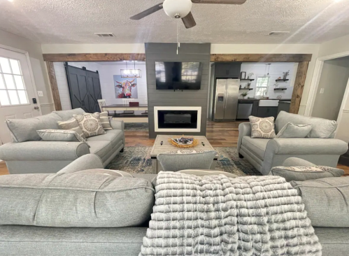 Cozy living room with gray sofas, a coffee table, and a modern fireplace, featuring a stylish decor and open layout.