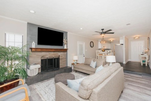 Cozy living room with a fireplace, comfortable seating, and an open layout leading to a dining area and kitchen.